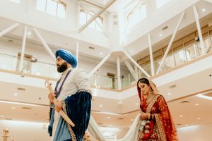 Traditional Sikh wedding ceremony taking place in bright modern temple interior.