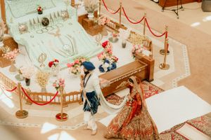 Aerial view of Sikh wedding ceremony with decorative roped area and floral arrangements.