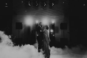 A romantic first dance surrounded by atmospheric fog and dramatic lighting at a wedding reception.