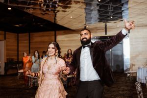 A couple in formal attire dancing enthusiastically at their wedding reception in an indoor venue.