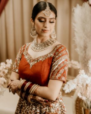 Elegant Indian bridal portrait showcasing traditional jewelry and red attire.