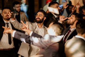 Energetic wedding guests celebrating and dancing at a lively reception party.