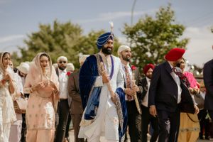 A group wearing traditional South Asian attire gathers outdoors at a Sikh wedding ceremony.