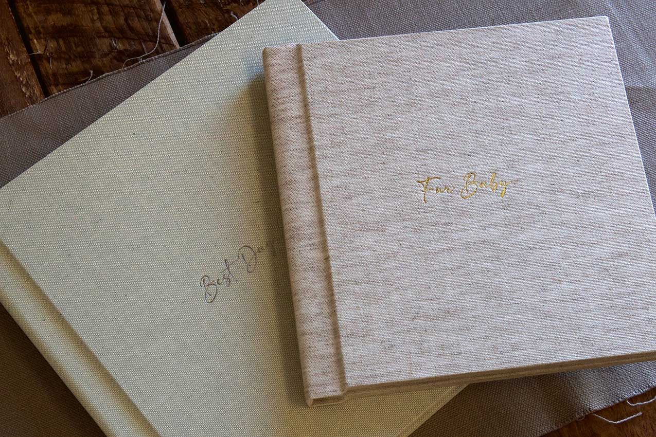 Row of minimalist beige linen photo albums arranged on a light surface.