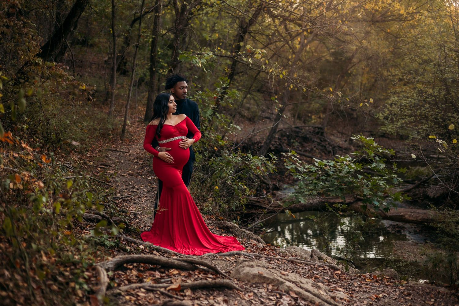 Man and pregnant woman in a red dress in the woods