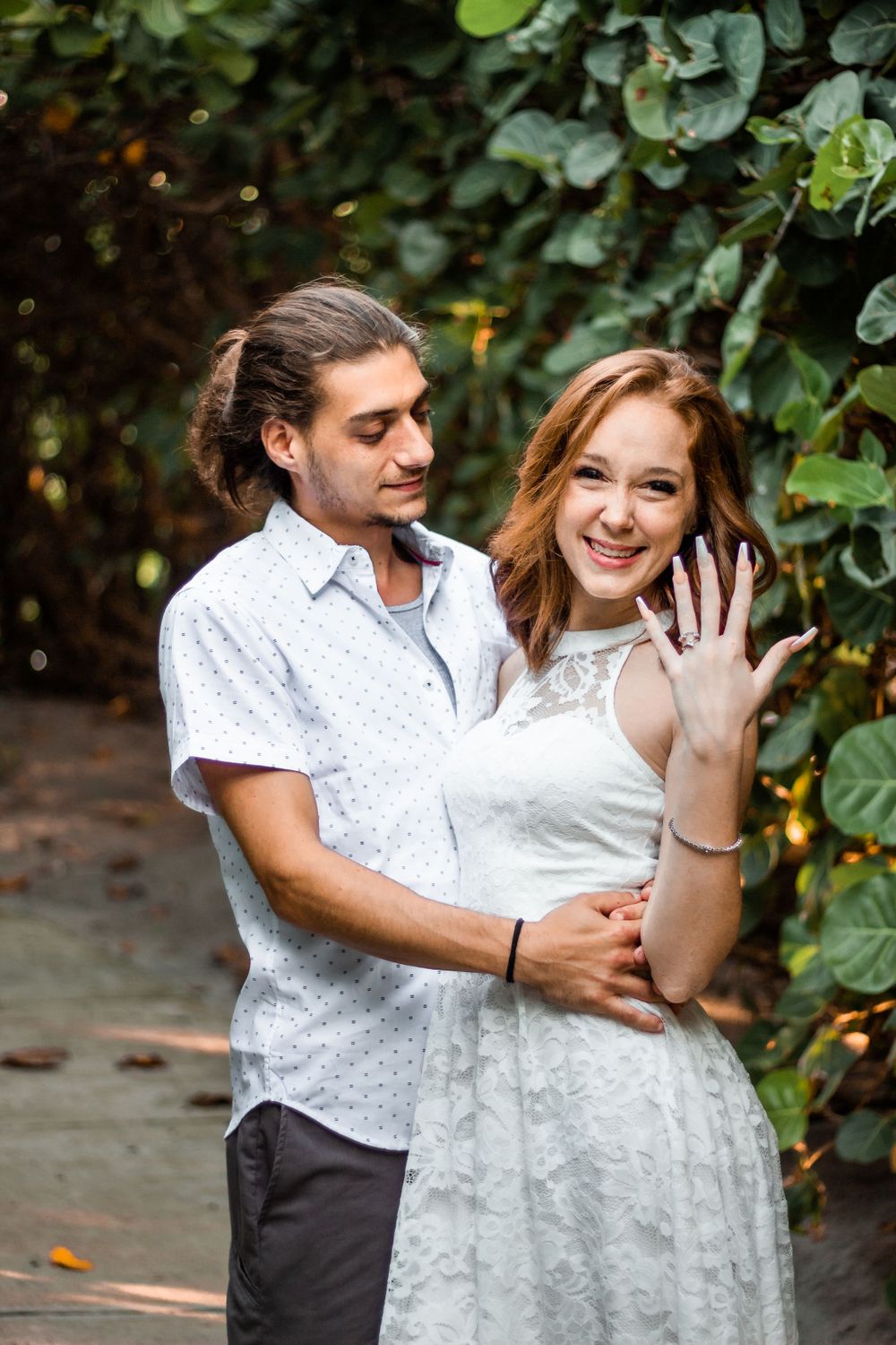 Engaged couple showing ring in garden setting with greenery backdrop in jupiter Florida on the beach at blowing rocks