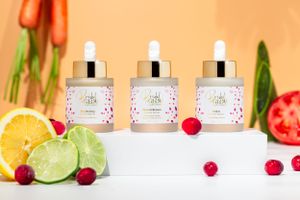 3 bottles of serum with tomato, aloe vera, carrots and citrus surrounding it