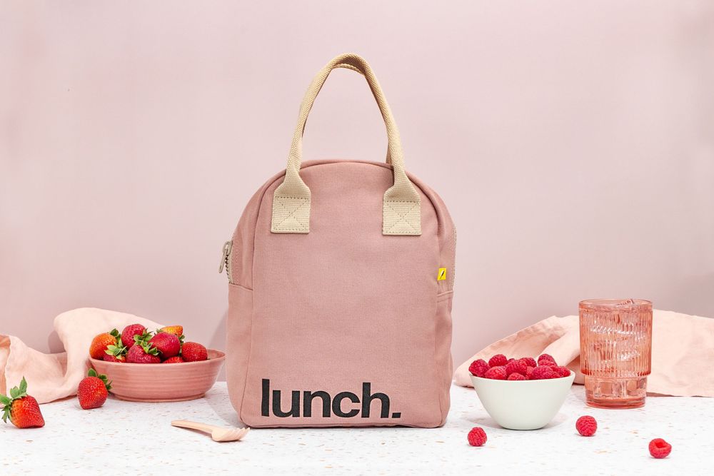 Mauve lunch bag with pink fruit and accessories beside it