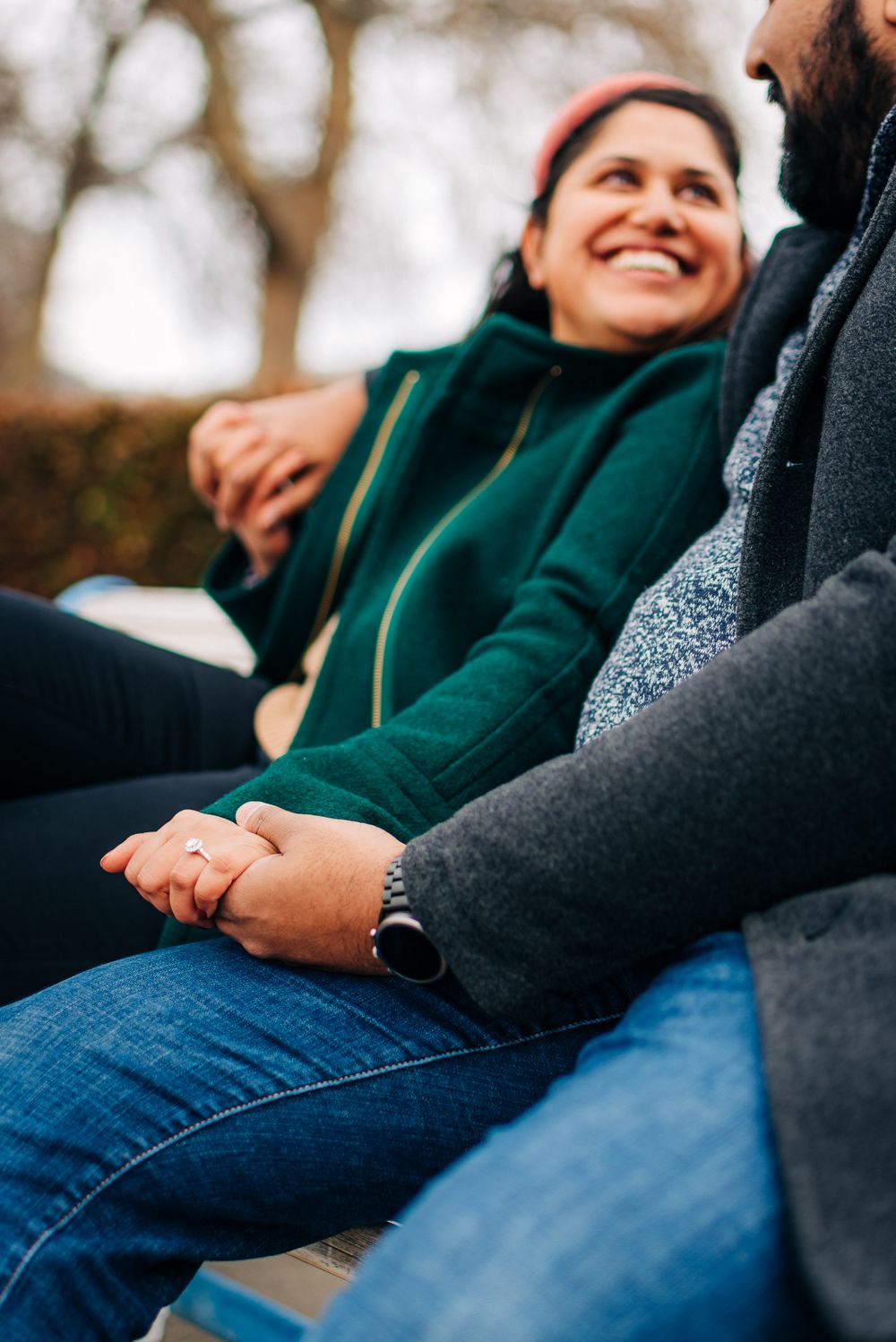 A couple in casual wear sharing an intimate moment outdoors, holding hands while sitting together.