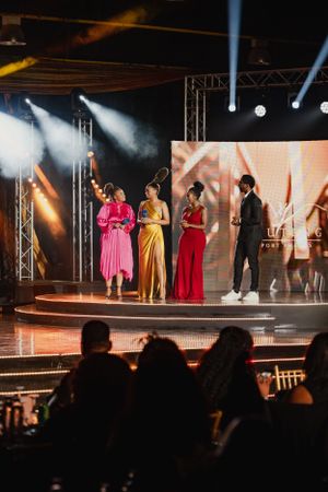 Stage performers in formal attire present during evening entertainment show with dramatic lighting.