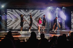 Dynamic dance performance on stage with artistic lighting and geometric patterns in background.