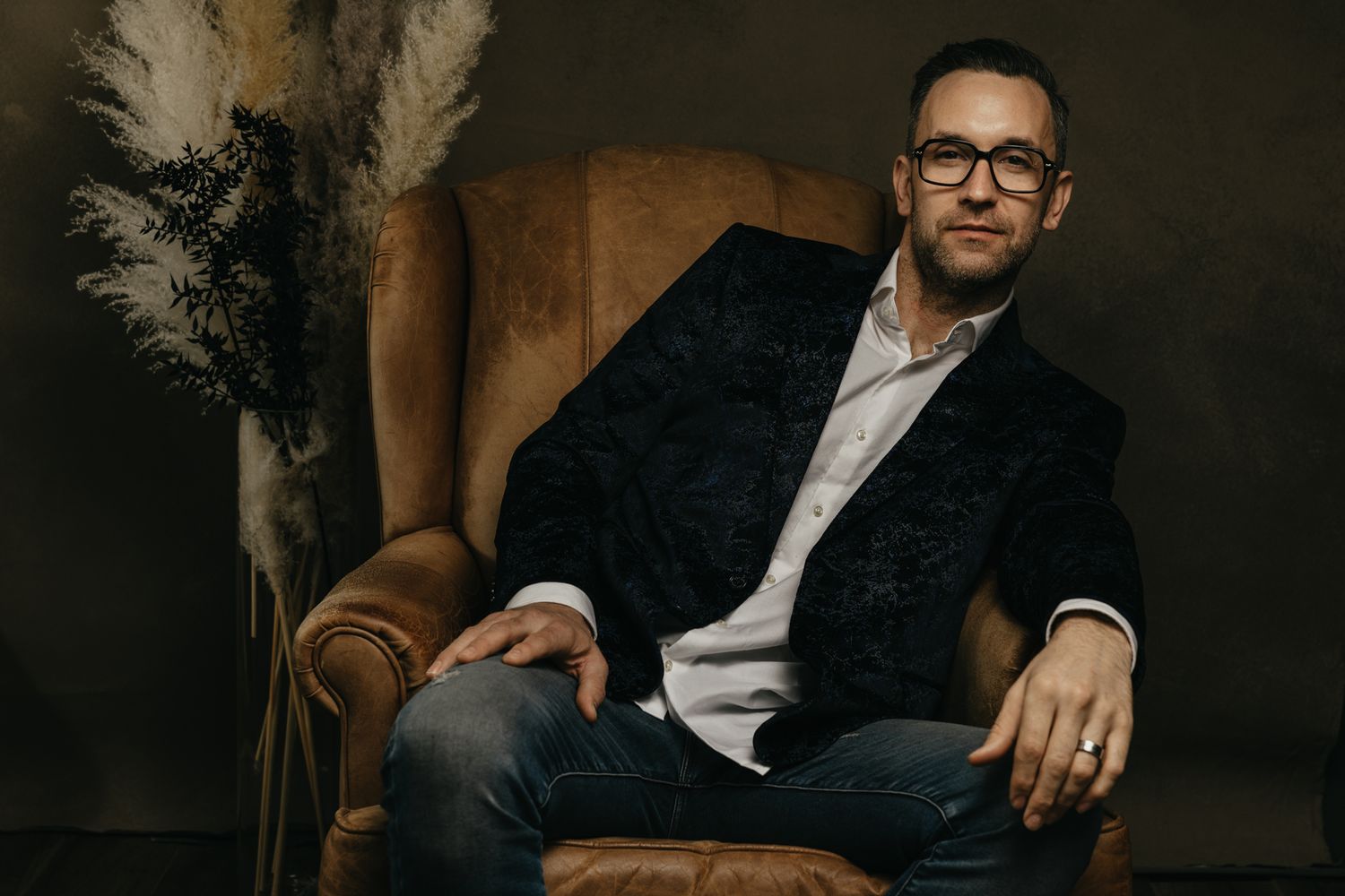 Professional studio portrait session featuring moody lighting and leather chair setup.