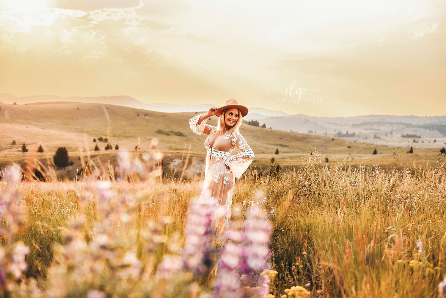 Woman wearing a gown and cowgirl hat in a flower field in the montana mountains