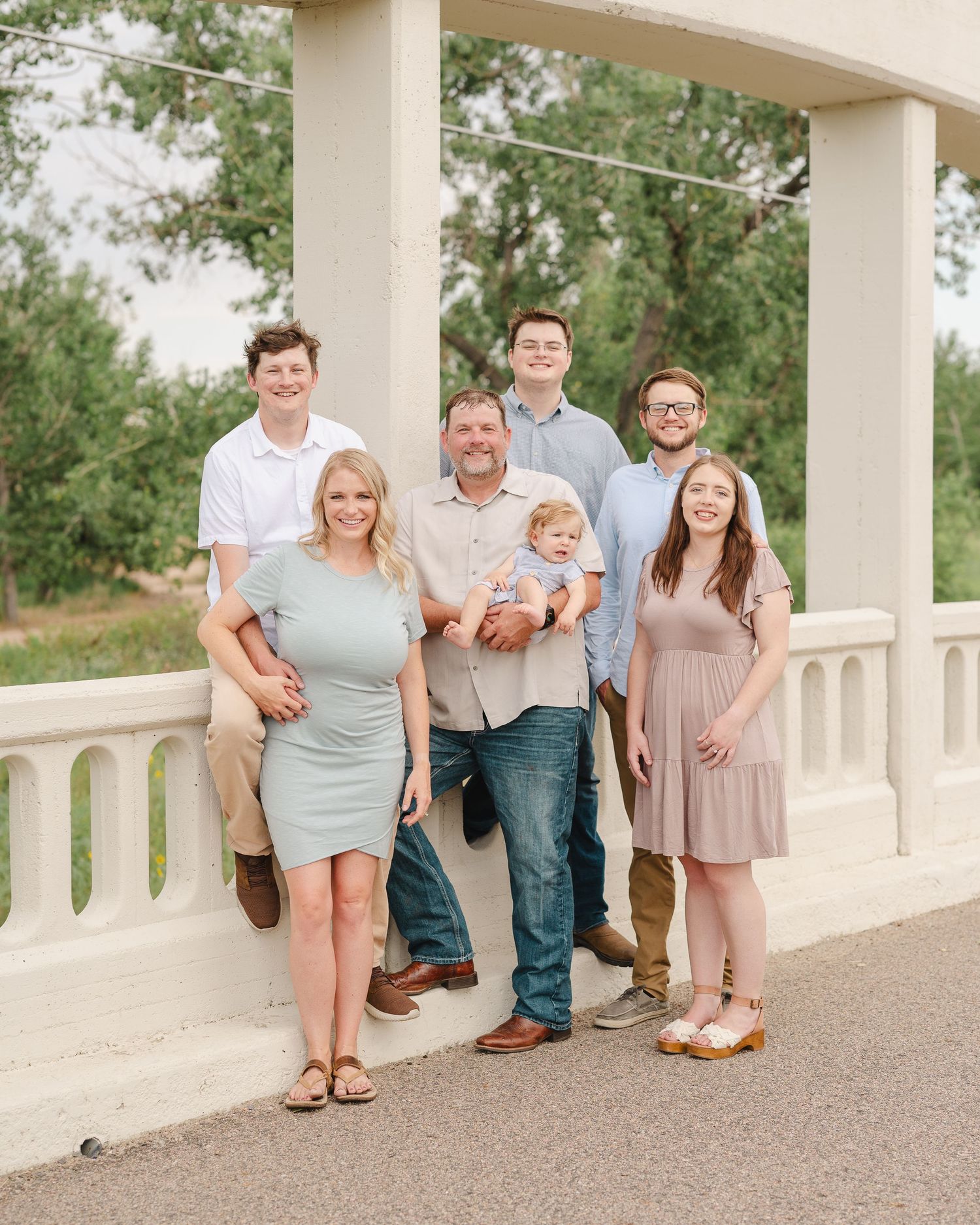 A multi-generational family group photo taken under a white columned structure outdoors.