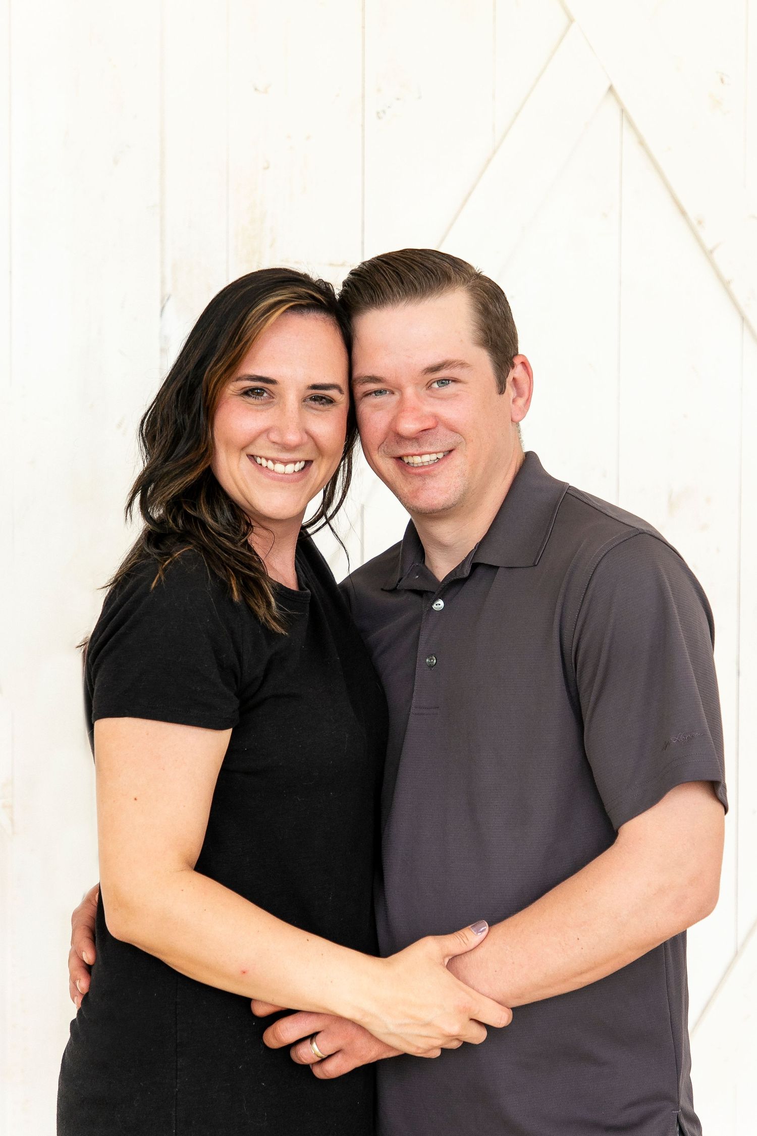 a man and a woman holding each others arms standing hip to hip, faces touching.