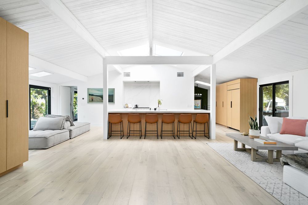 Open concept living space with white ceiling, light wood floors and kitchen island.