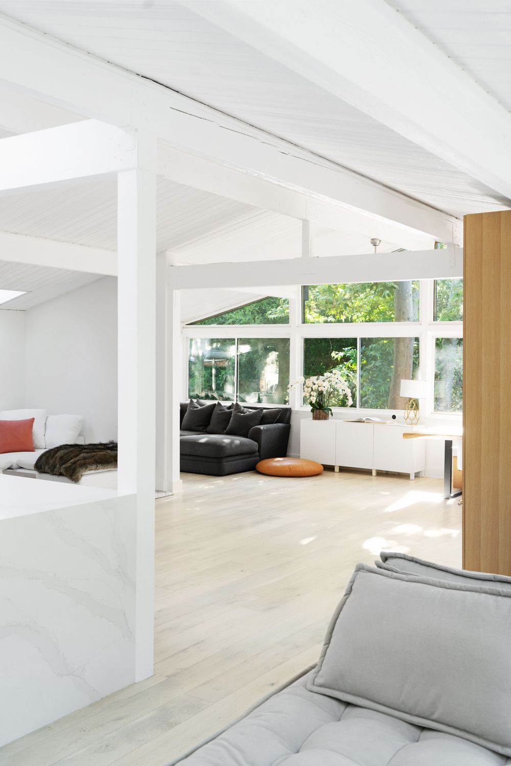 Open plan living area with white walls, structural beams and comfortable seating arrangements.
