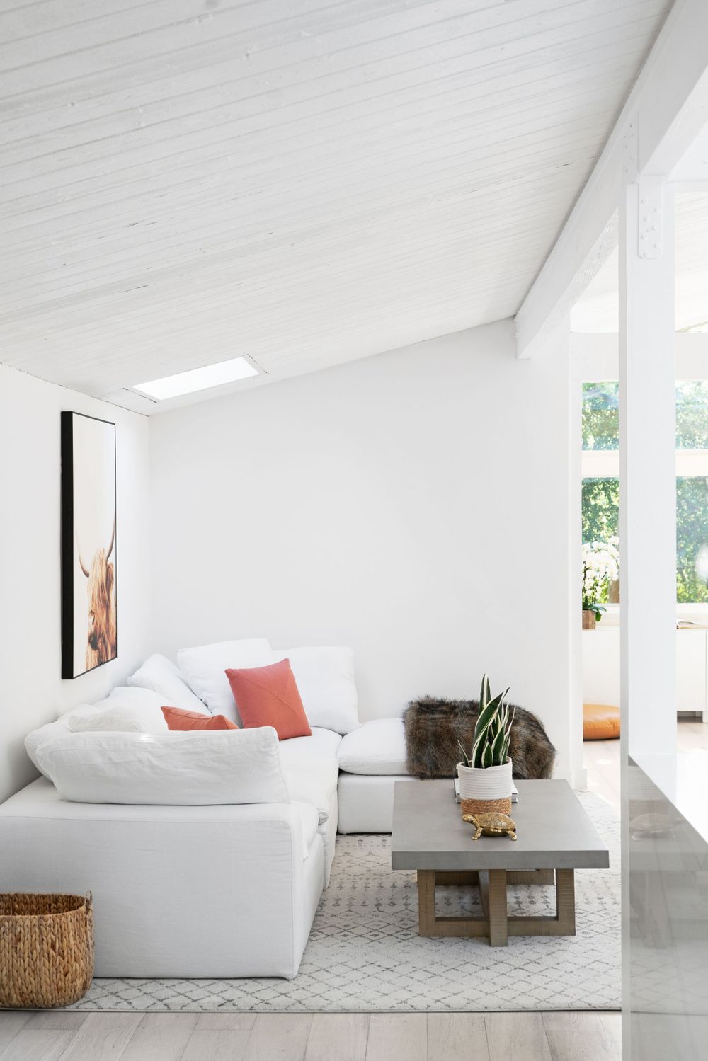 Minimalist white living room with plush sectional sofa and natural light streaming through windows.