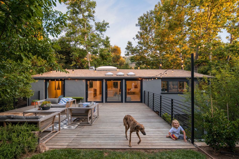 Modern gray house with expansive deck surrounded by fall foliage.