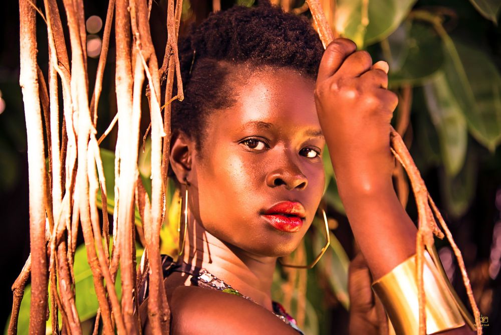Portrait in natural lighting with bamboo stalks creating dramatic shadows.