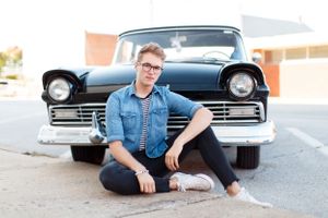 A casual portrait of boy with a classic Ford car featuring denim jacket and modern styling for a senior session in Springfield, MO..