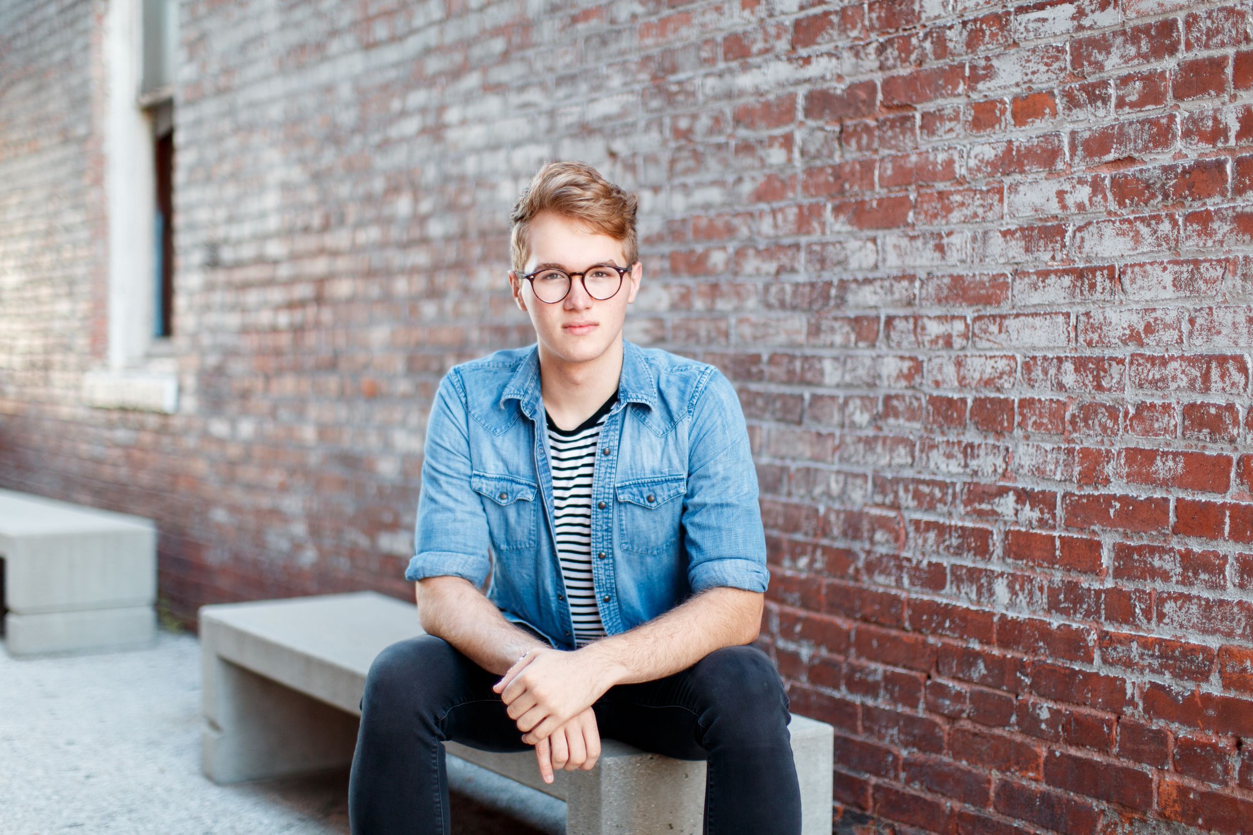 Senior boy sitting against a brick wall for a senior session in Springfield, MO.