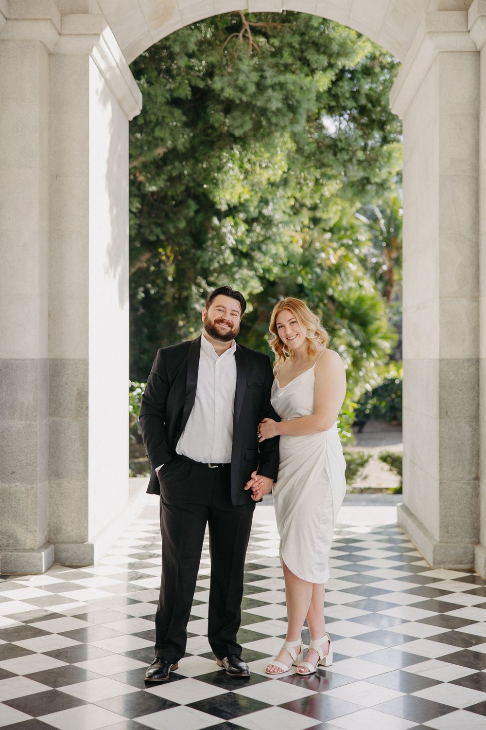 A formal portrait of a couple in an elegant archway with decorative stone columns.