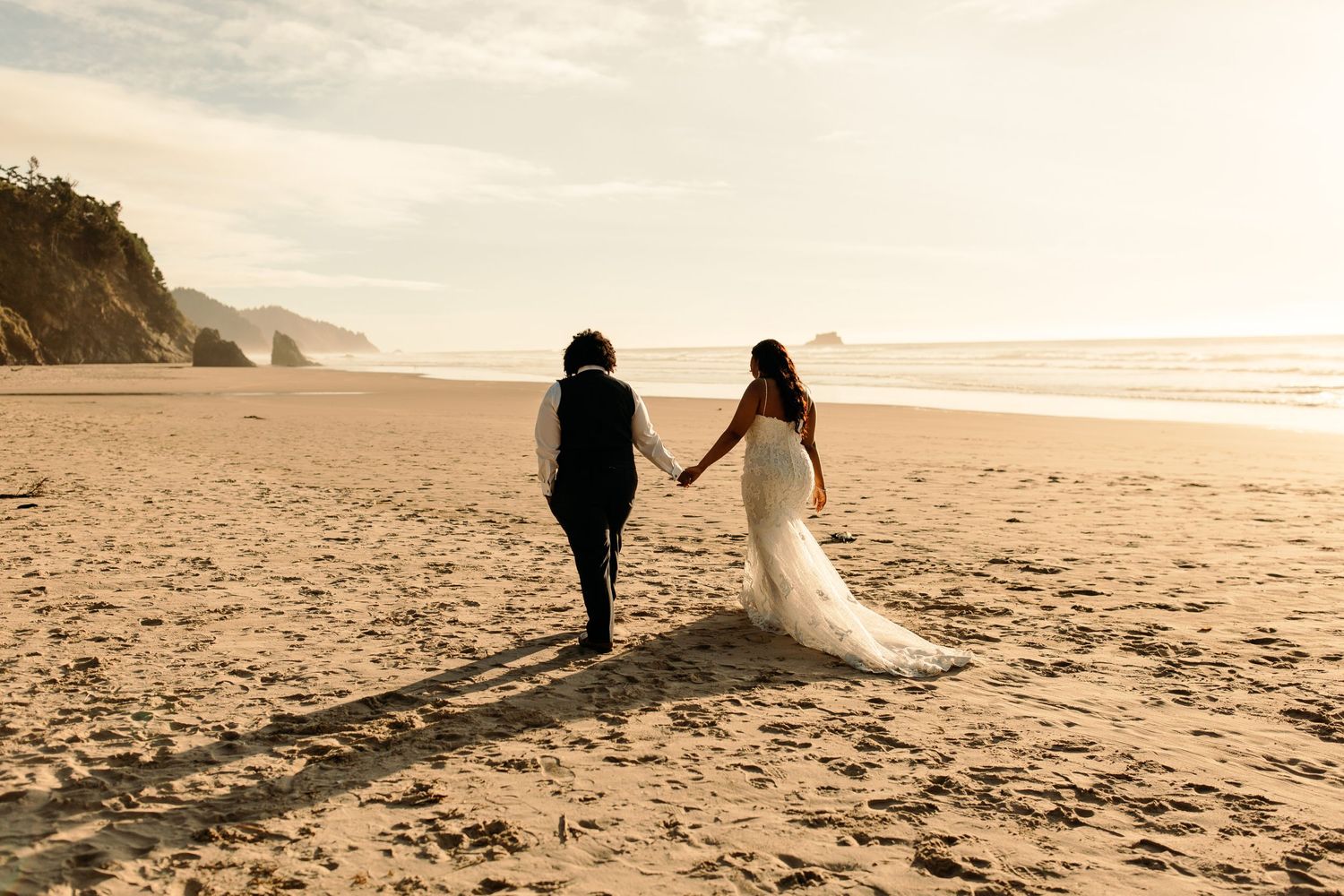 Oregon Coast Elopement at Hug Point Beach. Couple holding hands and walking along the water during sunset.