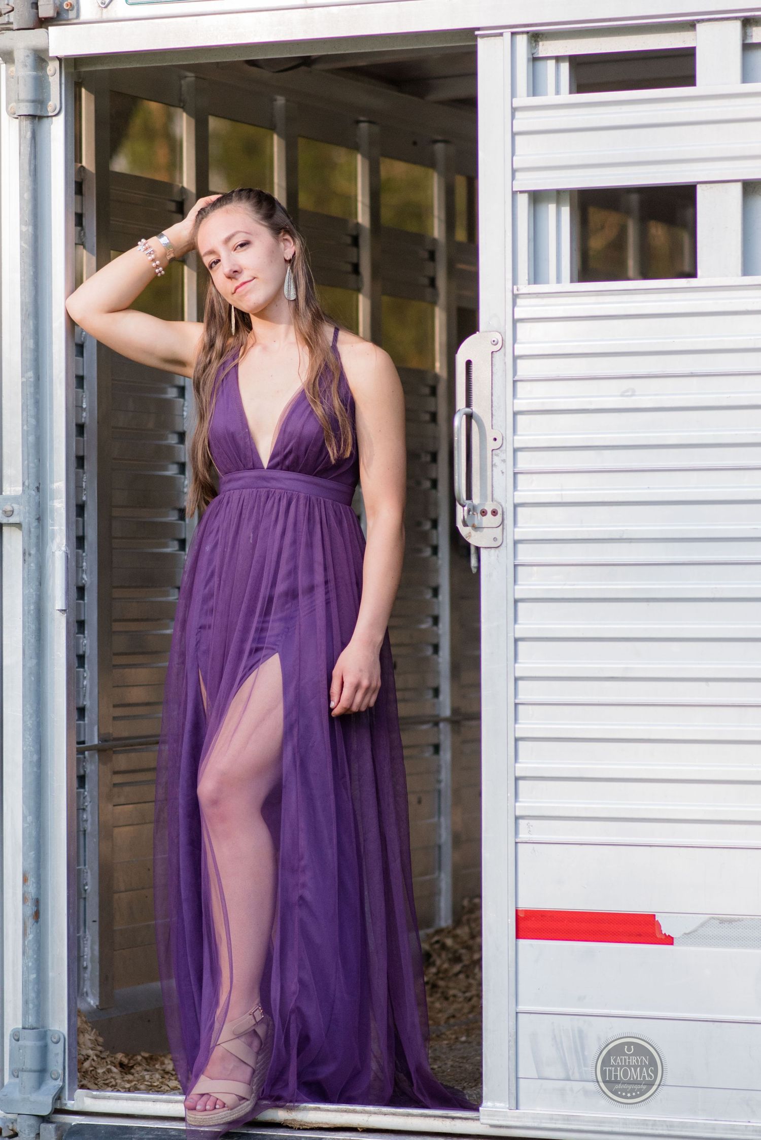 Someone stands in a doorway wearing a floor-length purple gown with a high slit.