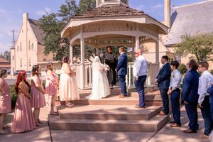 Wedding party gathers outside historic building for group photos.