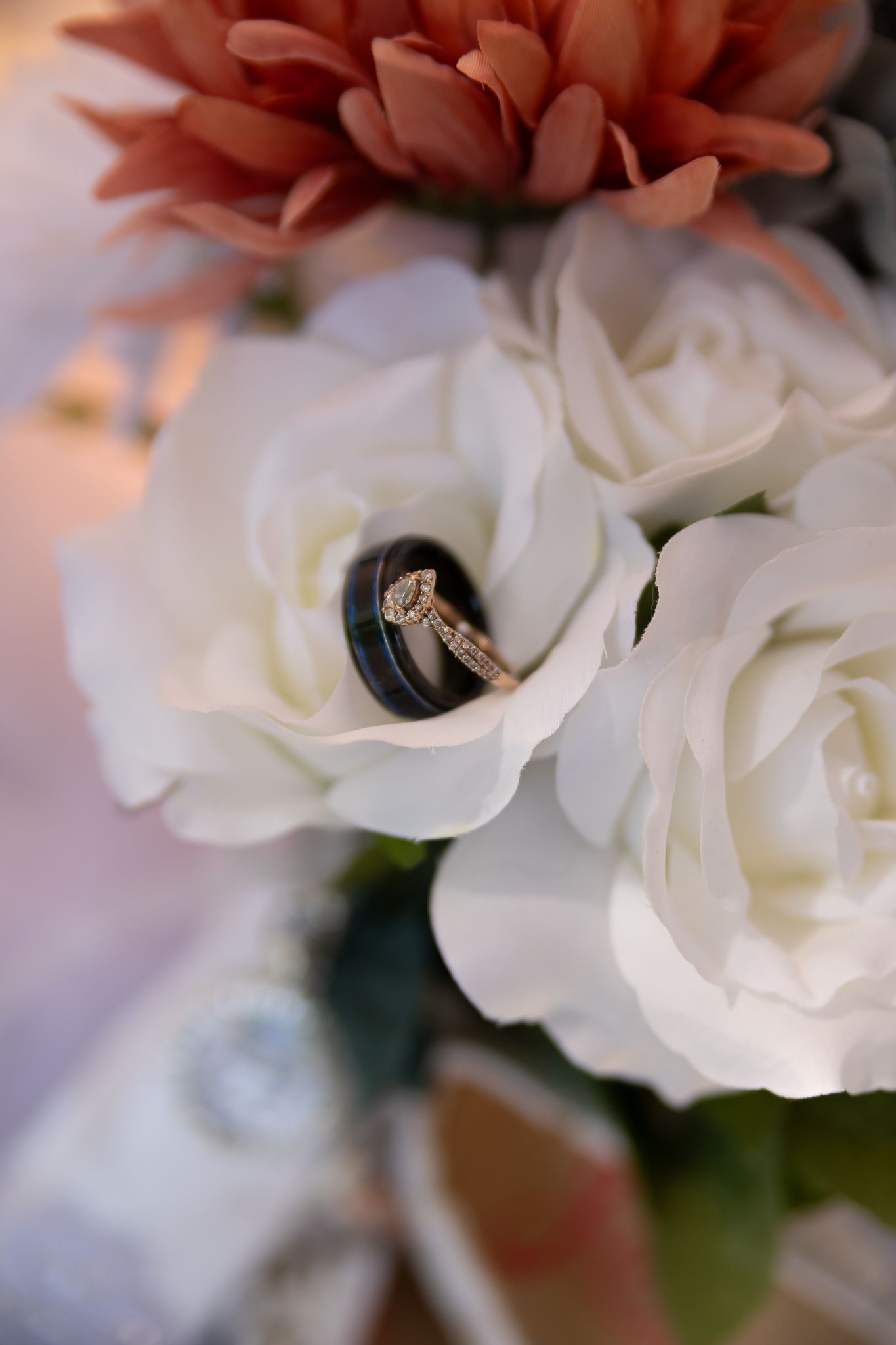 Macro shot of white roses and coral flowers in wedding bouquet arrangement.