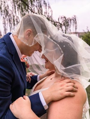 A tender moment between newlyweds sharing an intimate embrace under a delicate veil.