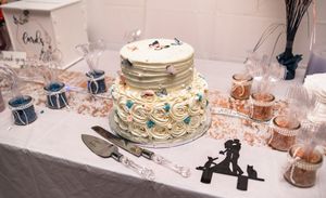 Wedding cake display with vintage cake toppers and place settings on a white tablecloth.