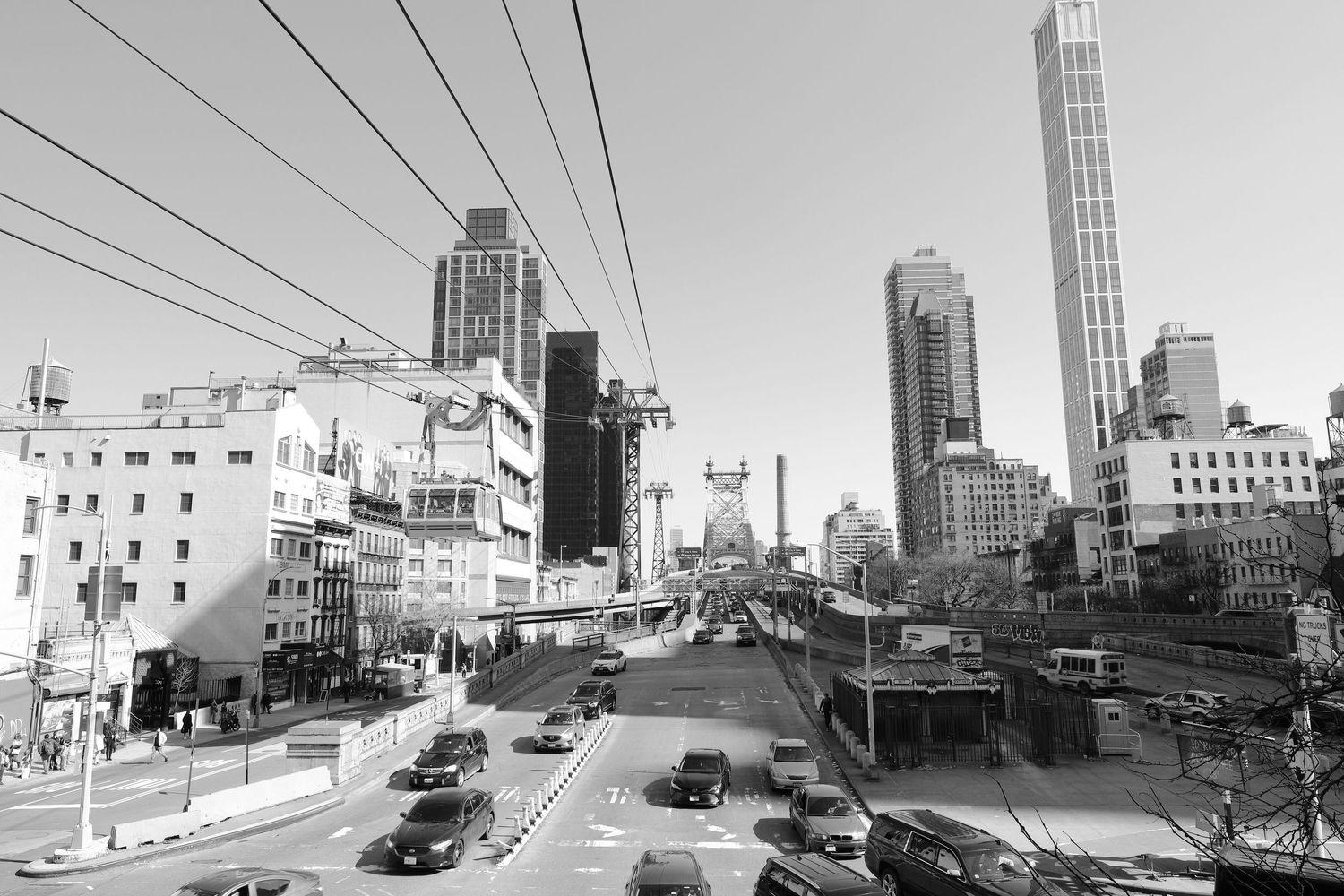 Black and white urban street view of Manhattan with power lines and modern skyscrapers.
