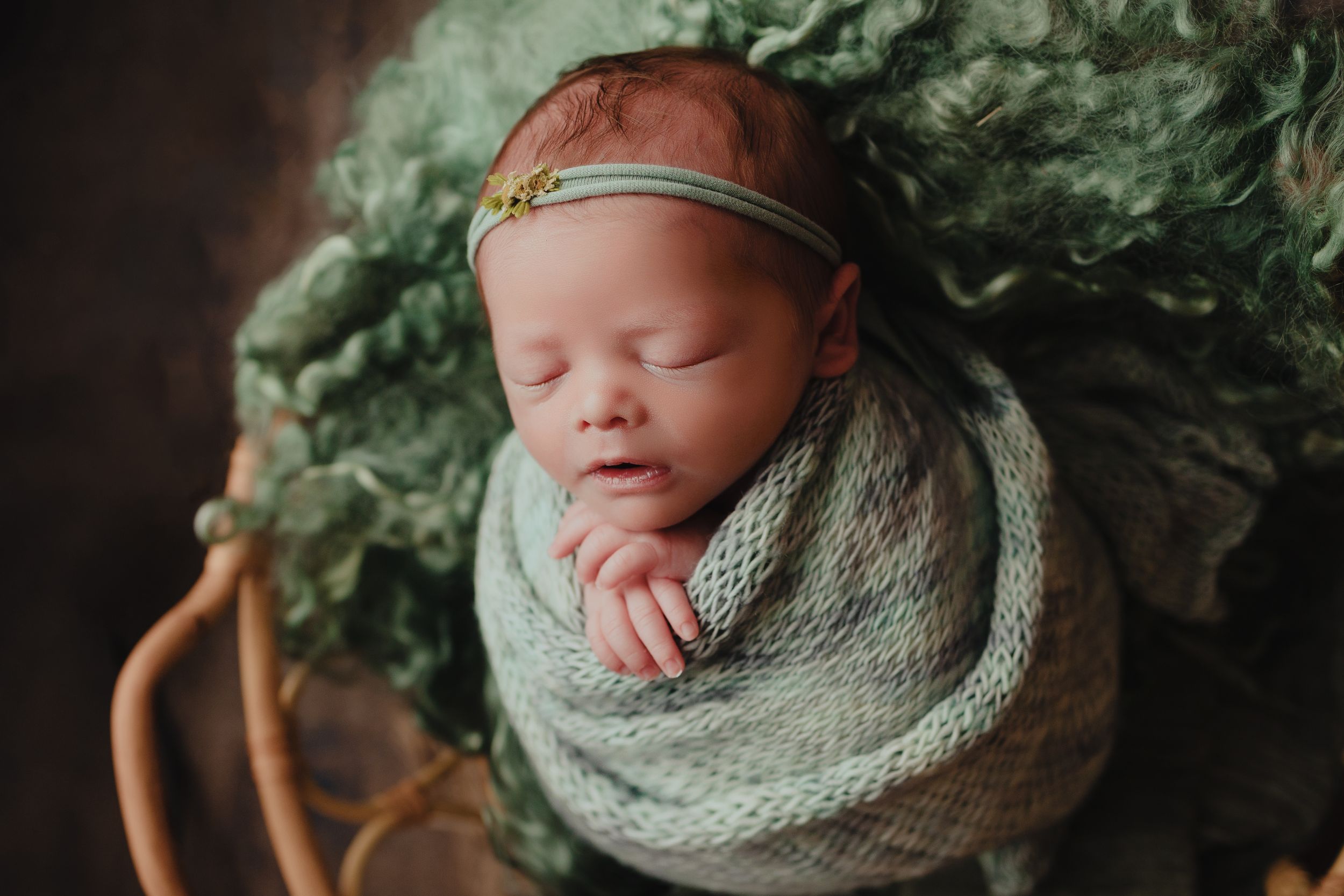baby girl wrapped in basket in green