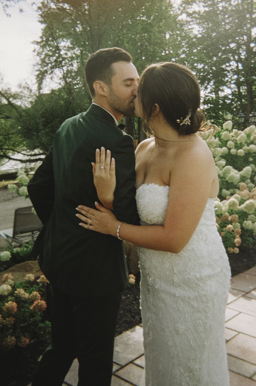 A tender wedding day moment shared between the couple in a garden with hydrangeas.