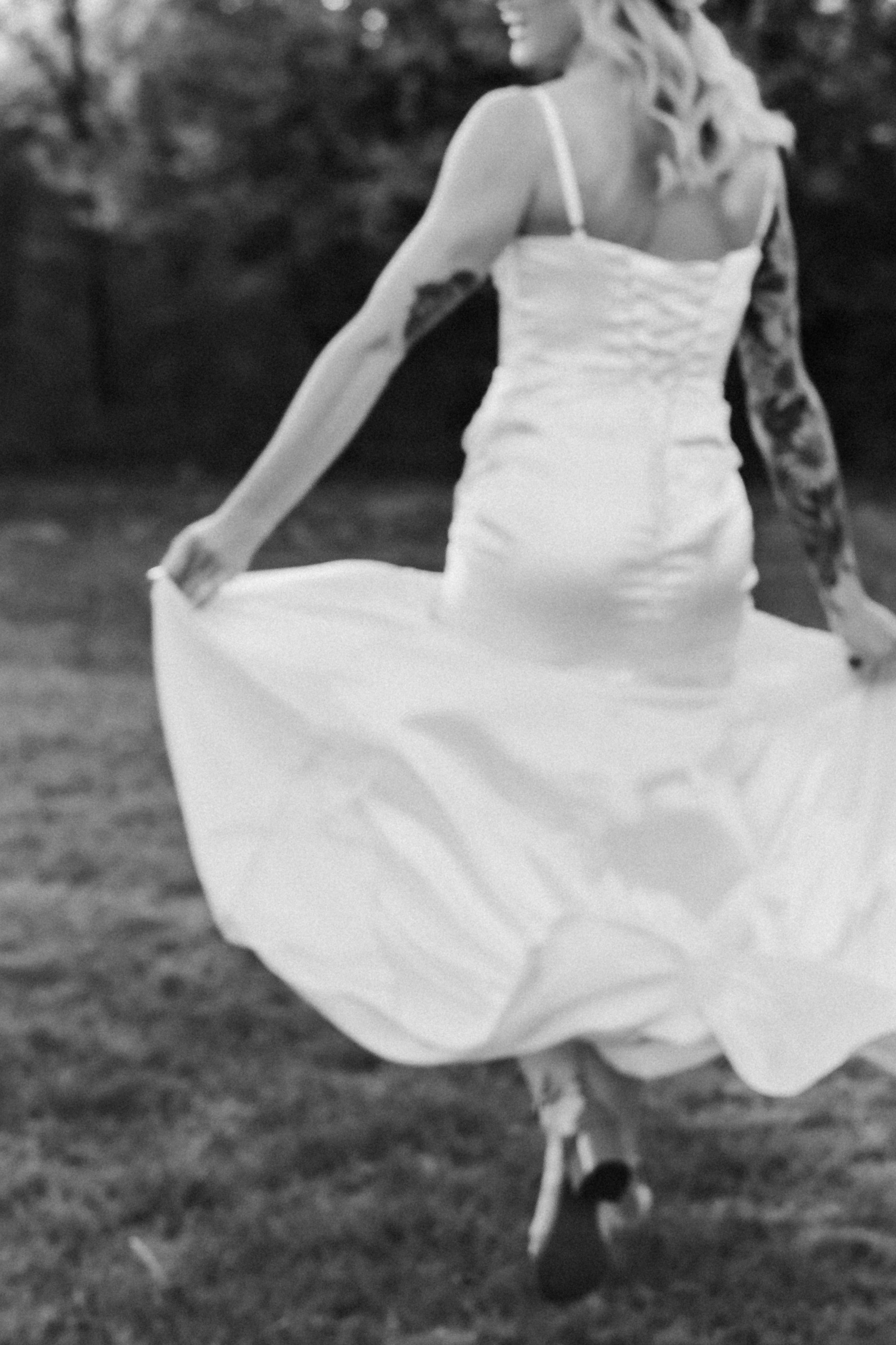a blurry image of the back of a bride while she runs away holding her dress up
