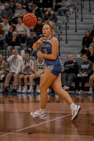 A basketball player in blue uniform handles the ball during competitive game action.