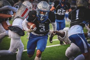 Football player carrying ball through defenders during intense game action.