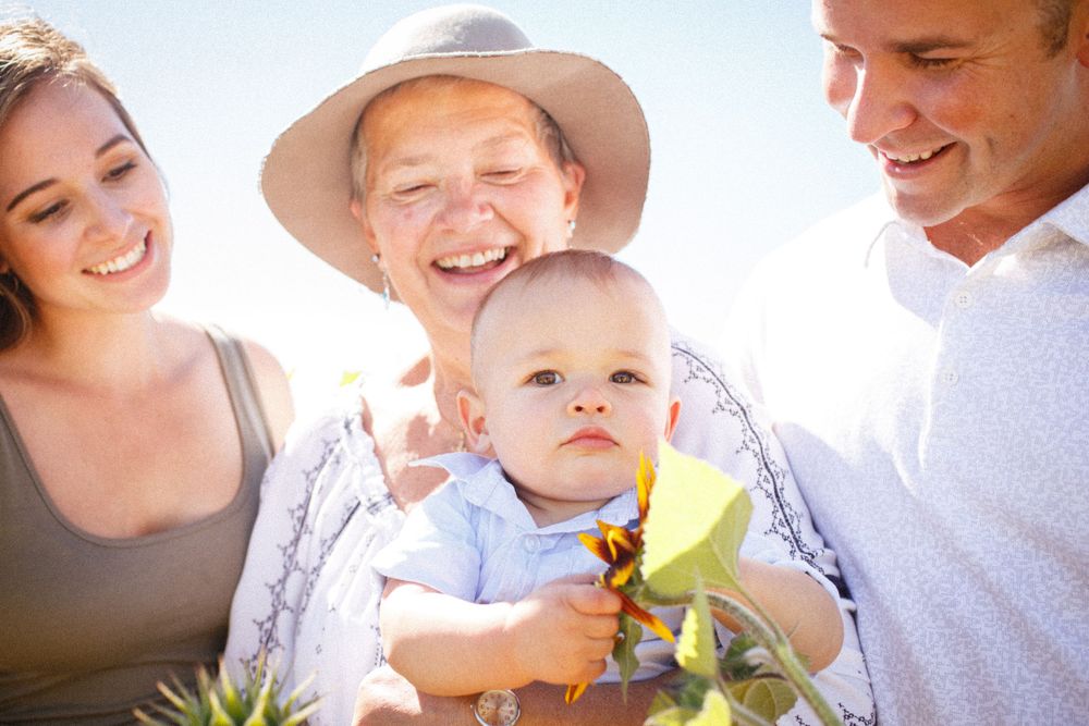Snohomish extended family photo shoot: A grandma holds her grandson and the young boy's parents stand on either side of her