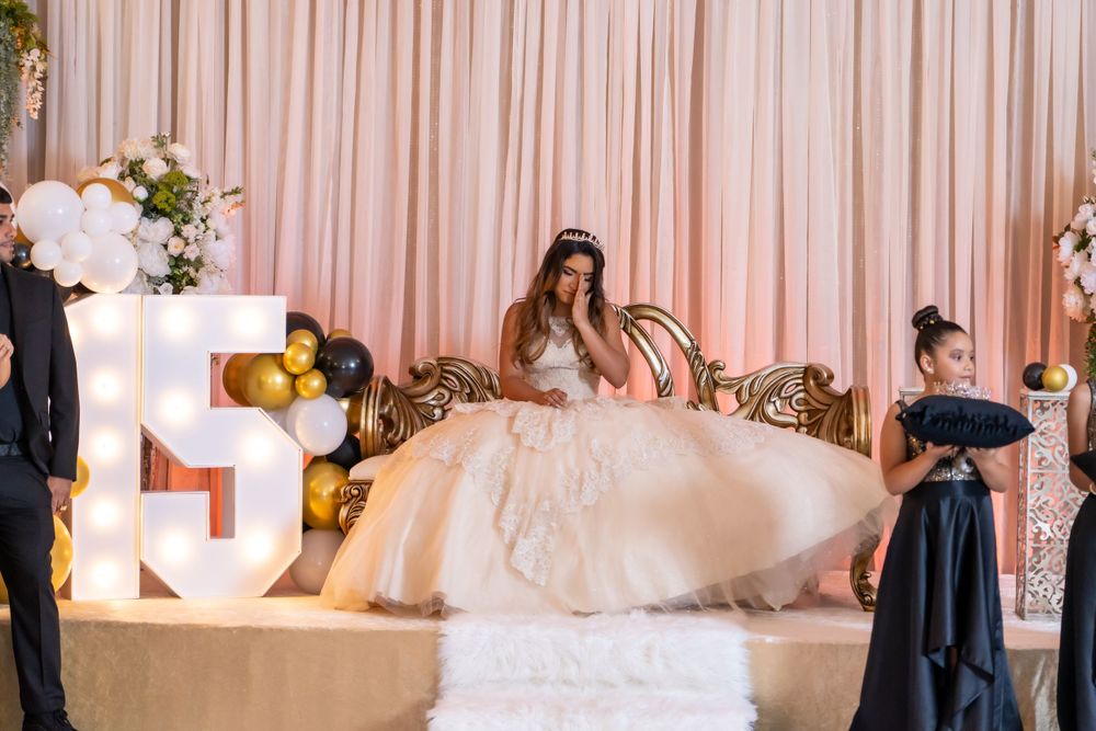 Celebration setup with illuminated letters, pink drapes, and gold balloon decorations.
