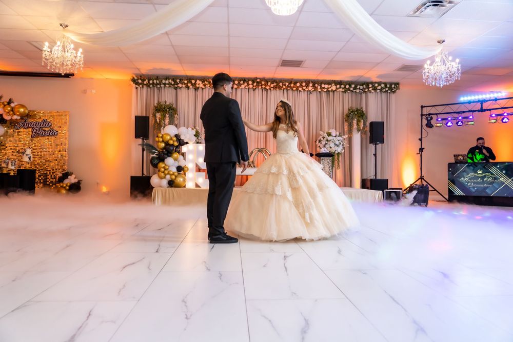Elegant couple shares first dance at wedding reception with decorative backdrop and ambient lighting.