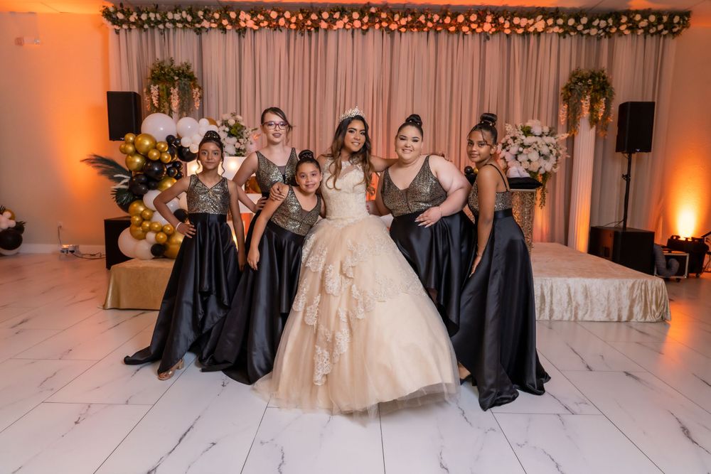 Wedding party poses together with bridesmaids in navy gowns and bride in champagne ballgown.