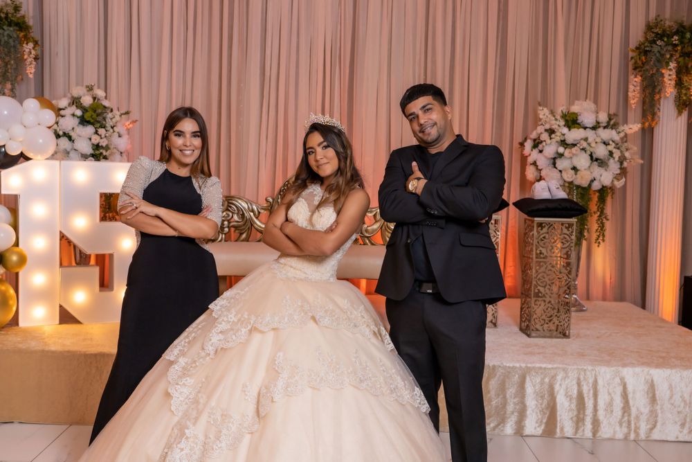 Wedding party members pose by illuminated decorations and floral arrangements at reception venue.