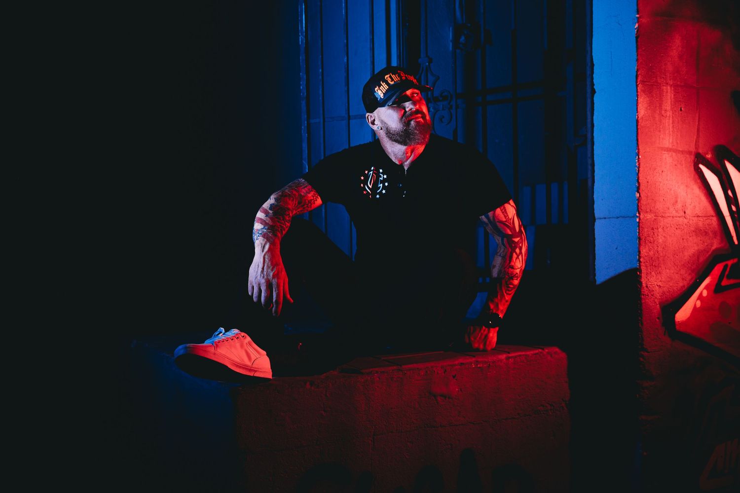 Dramatic portrait in dark setting with red and blue lighting creates mysterious atmosphere.