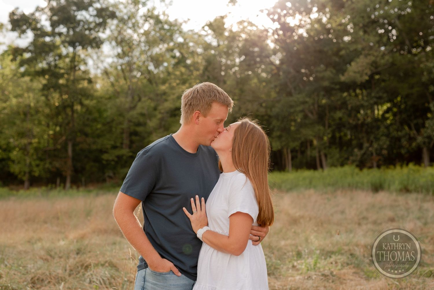 A tender moment between a couple standing in a field during golden hour.