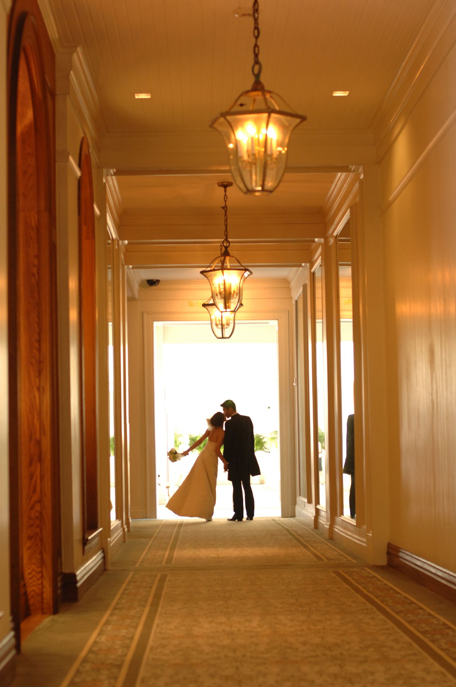 Romantic bride and groom silhouette kissing at end of elegant chandelier-lit hallway.
ハワイウェディング
ハワイ挙式