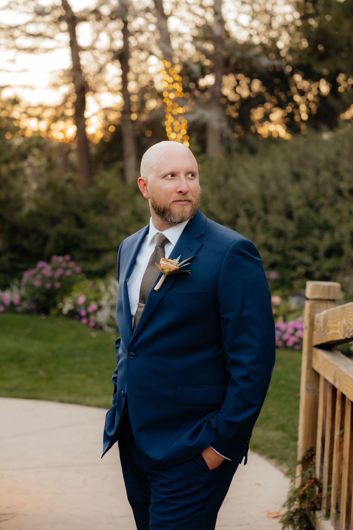 Groom looking over shoulder on a bridge in a garden