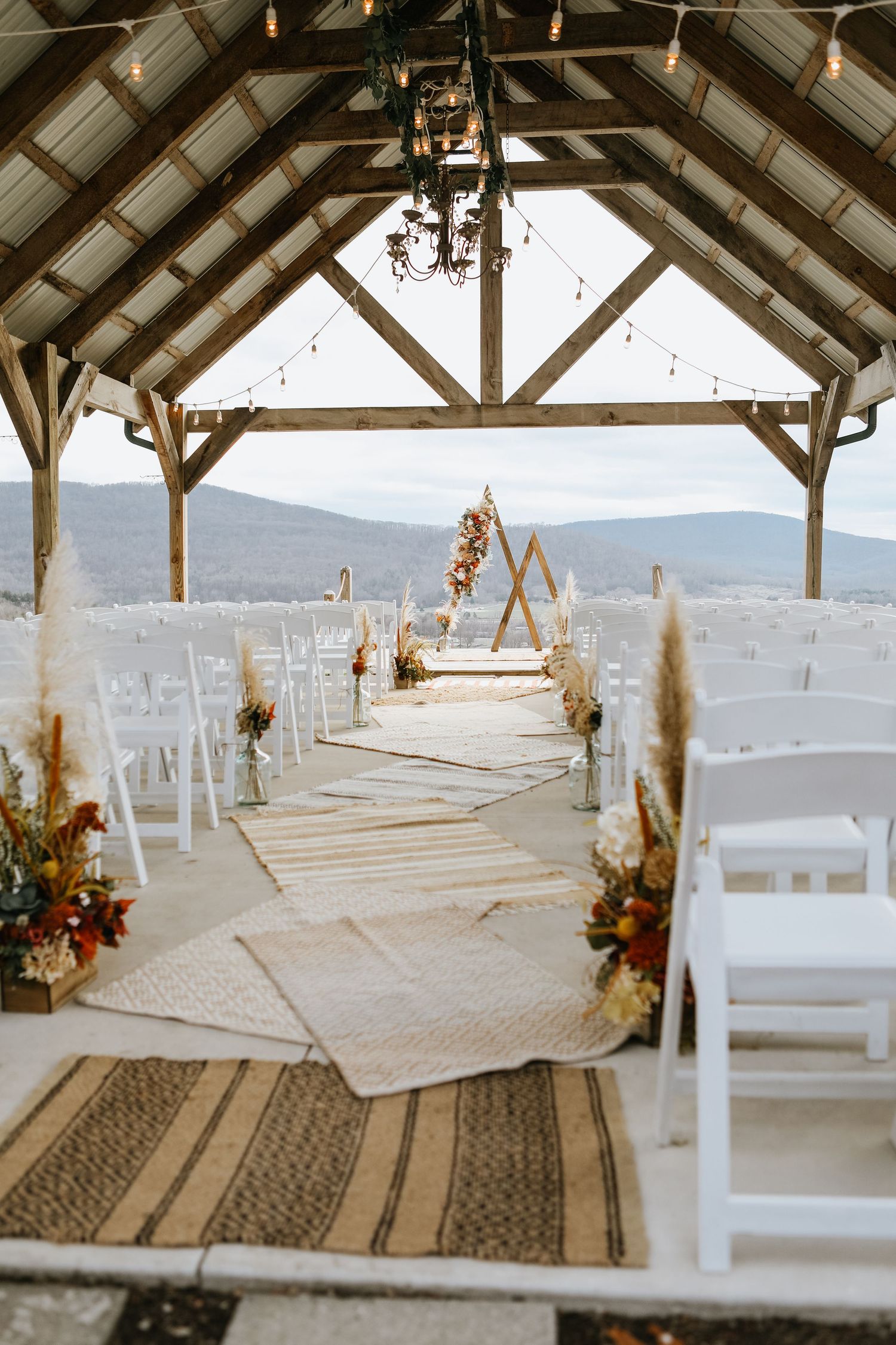 White chairs arranged in rows under a wooden pavilion for an outdoor ceremony.