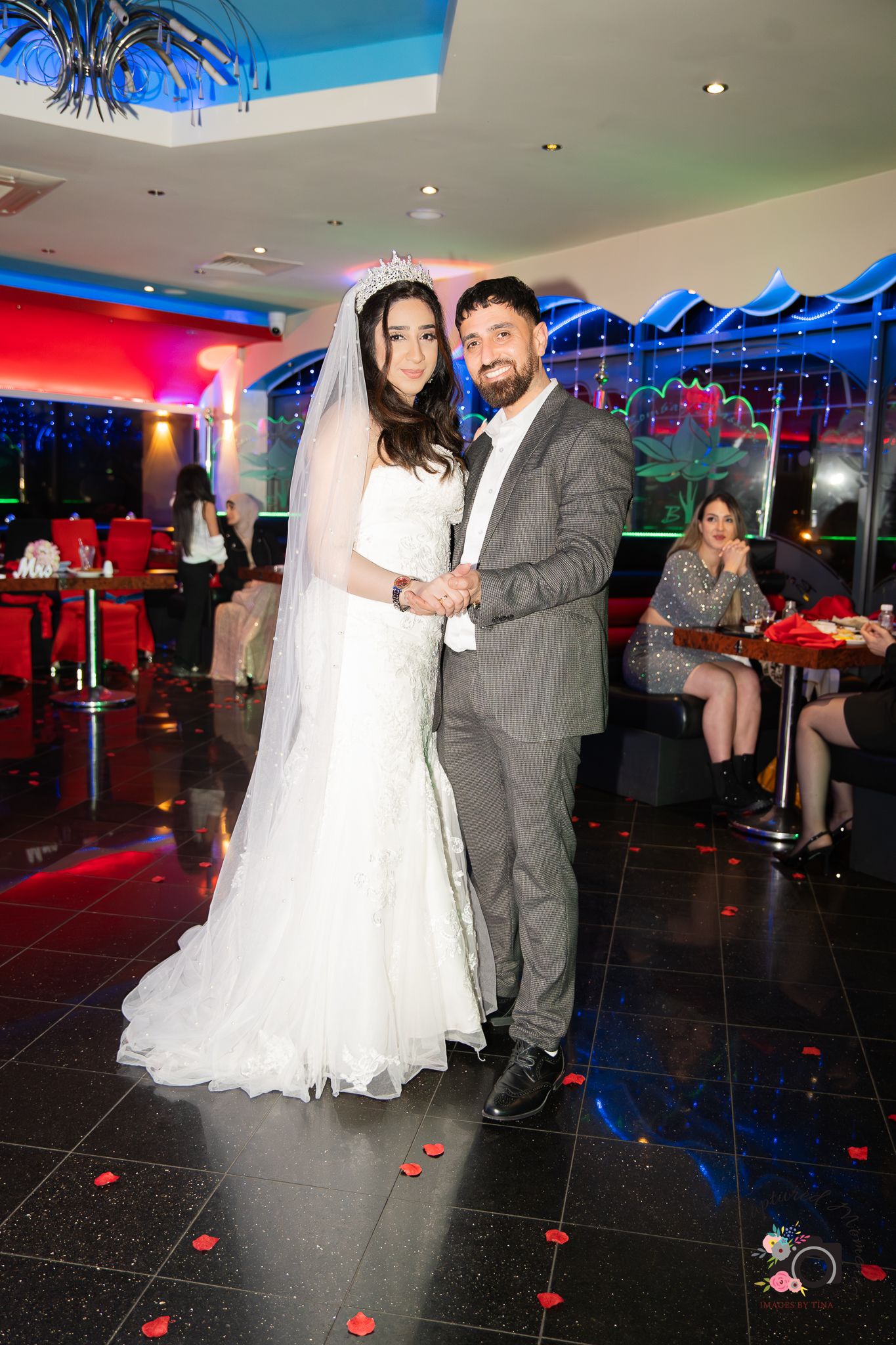 Wedding celebration in modern venue with colorful lighting and black tile floor.